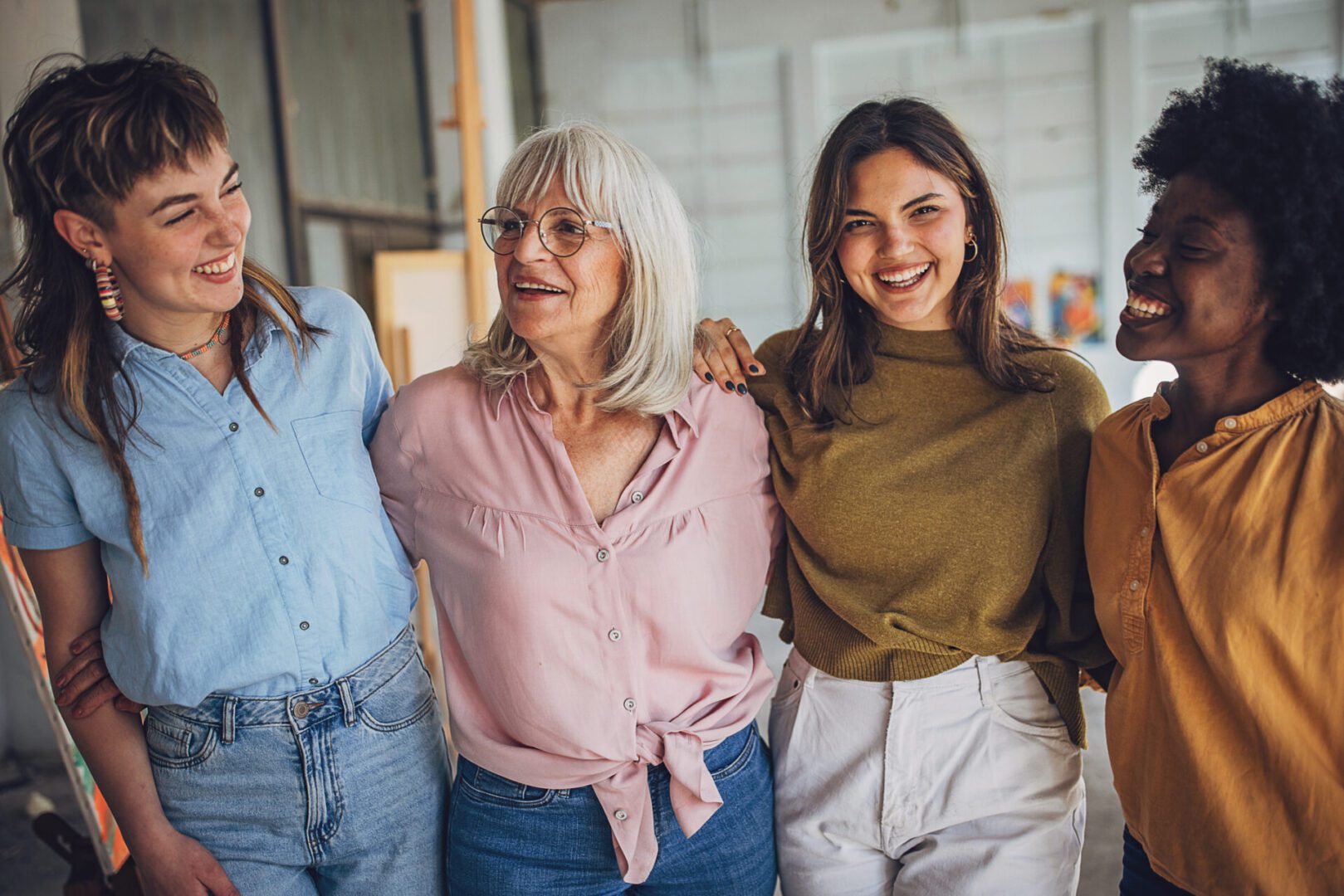Smiling art teacher and her diverse group of students enjoying a collaborative painting session in a bright, airy studio setting